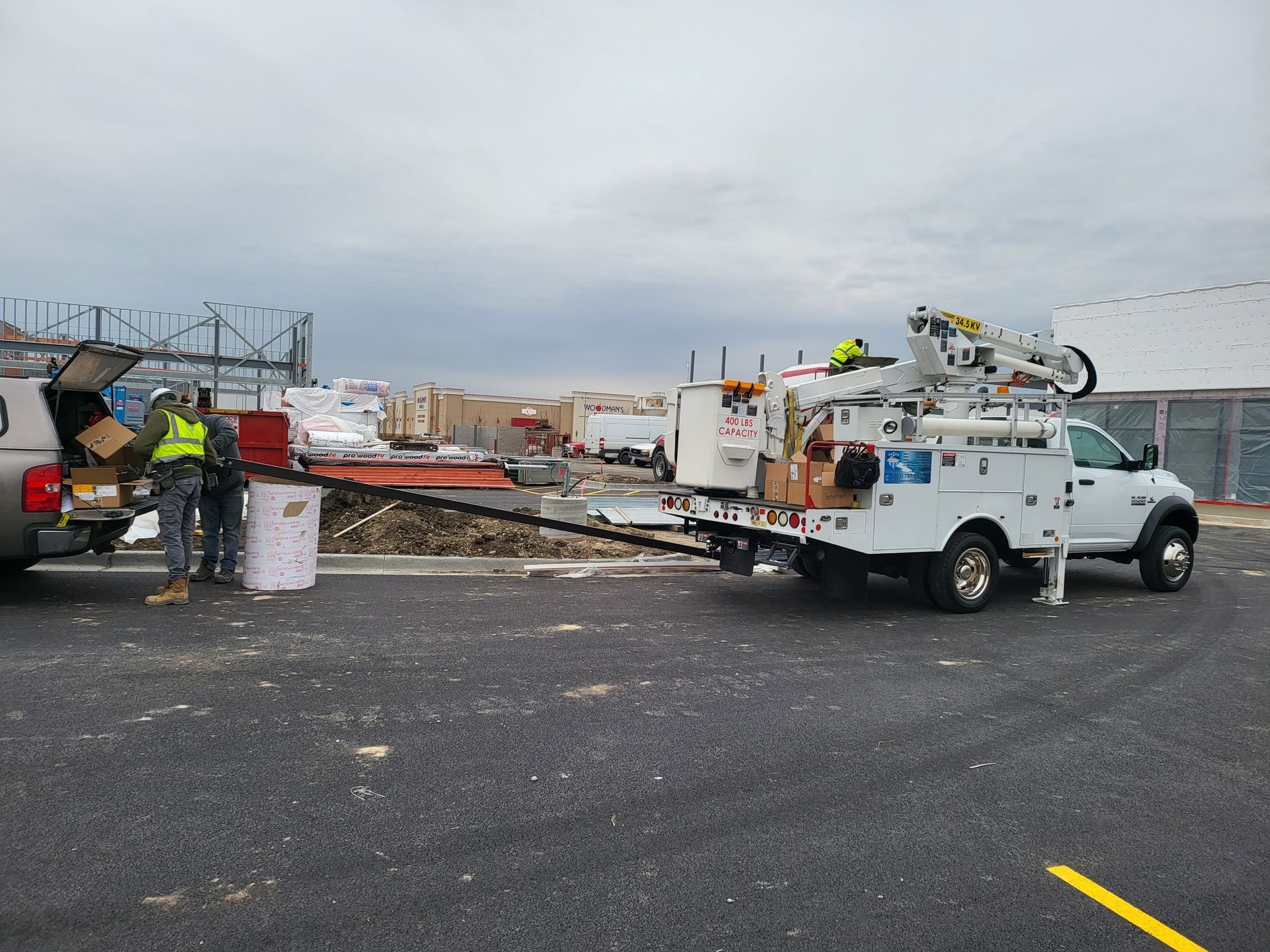 A white truck with a crane on the back is parked in a parking lot.