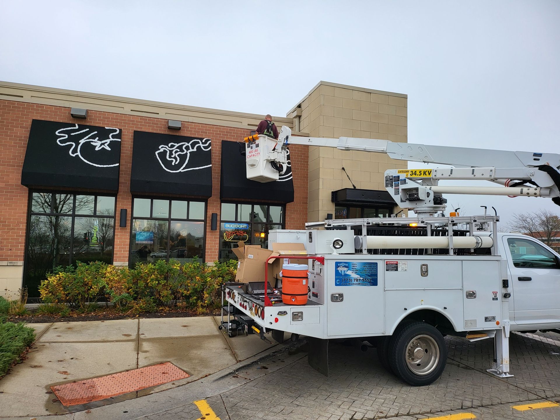 A white truck with a crane on the back is parked in front of a building.