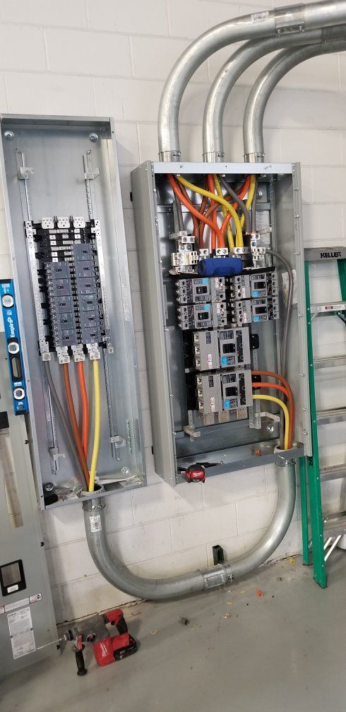 A electrical box is being installed on a wall next to a ladder.