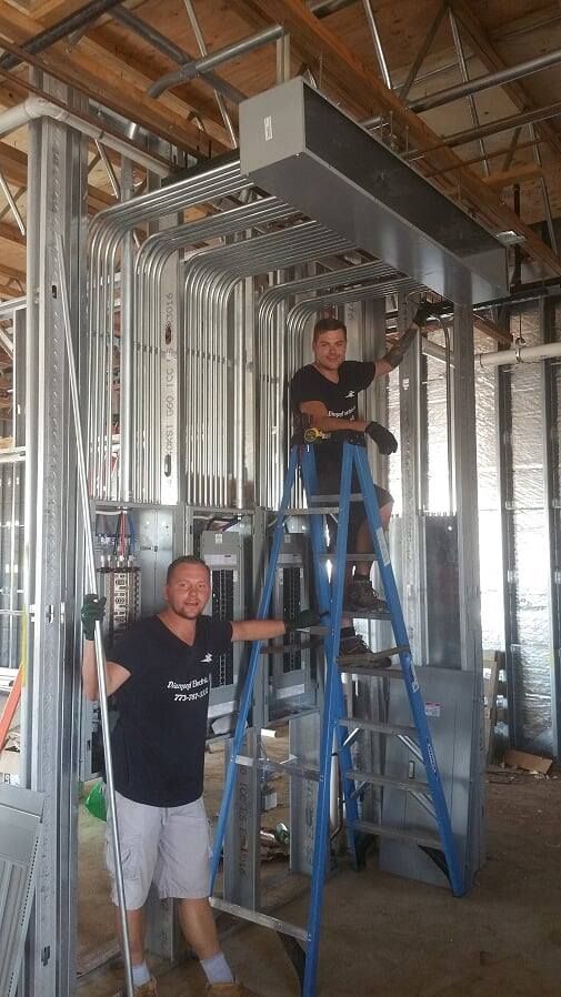 Two men are standing on ladders in a building.