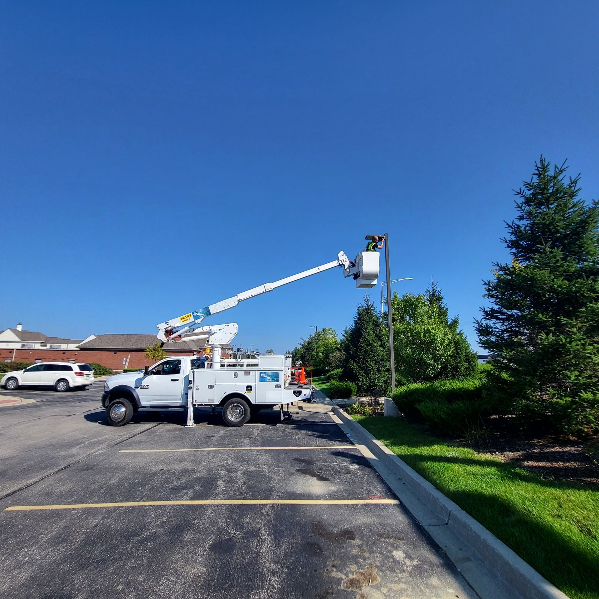 A white truck with a crane attached to it is parked in a parking lot