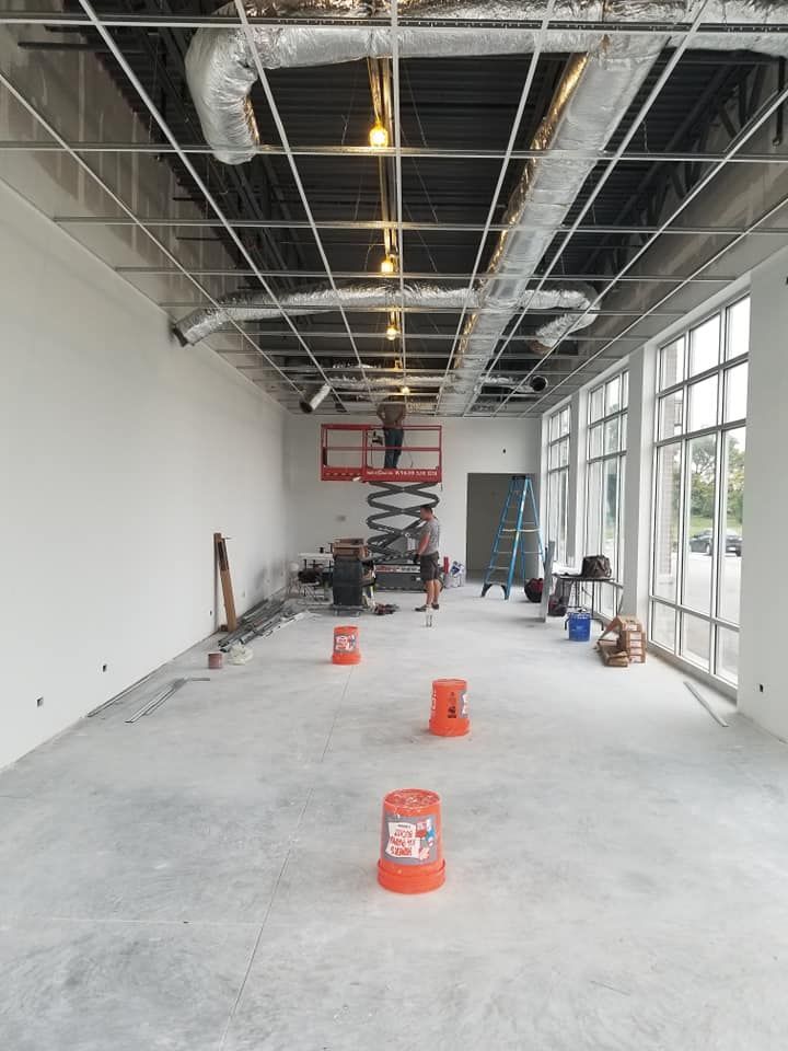 A large room with a lot of windows and a man on a scissor lift.