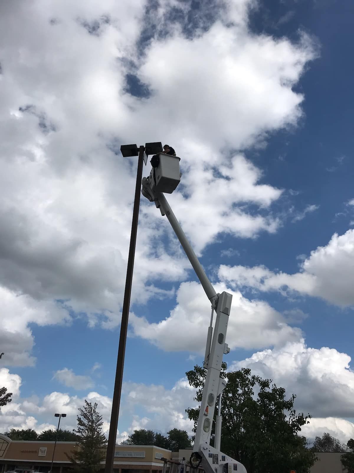 A man is working on a street light with a crane.