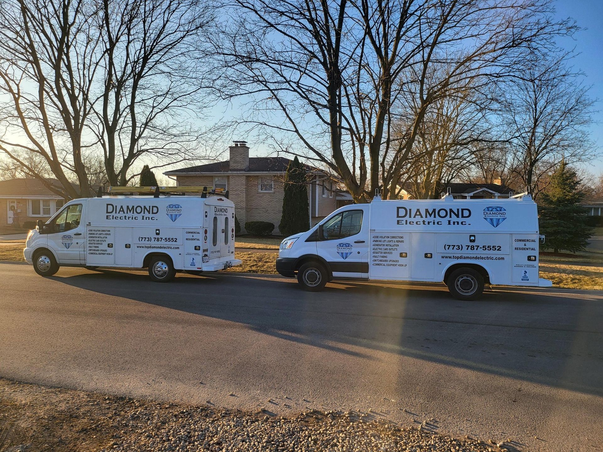 Two white vans are parked on the side of the road.