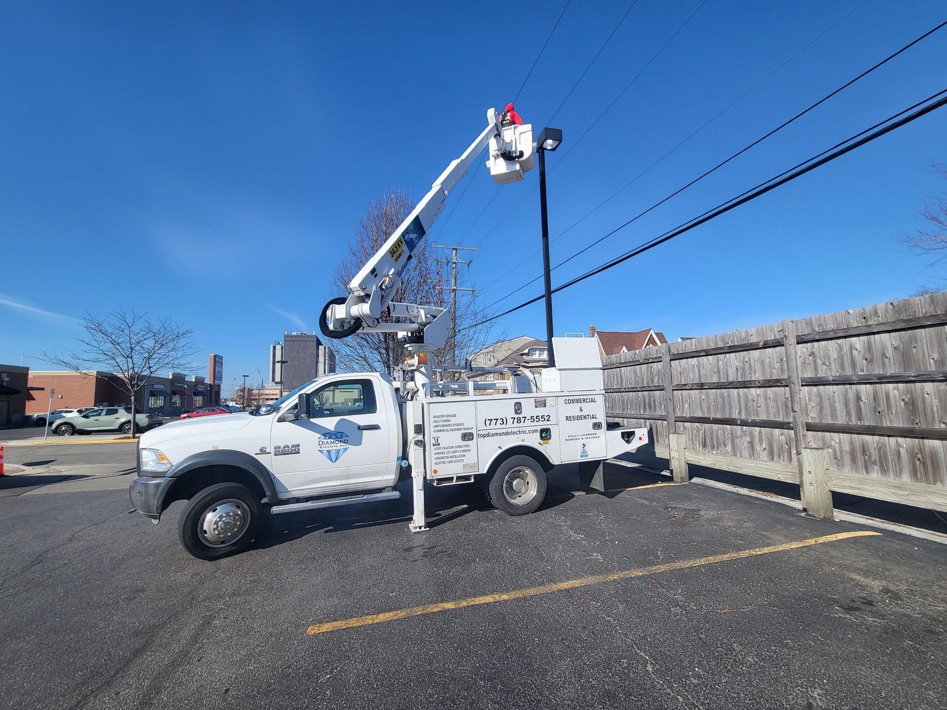 A white truck with a bucket on top of it is parked in a parking lot.