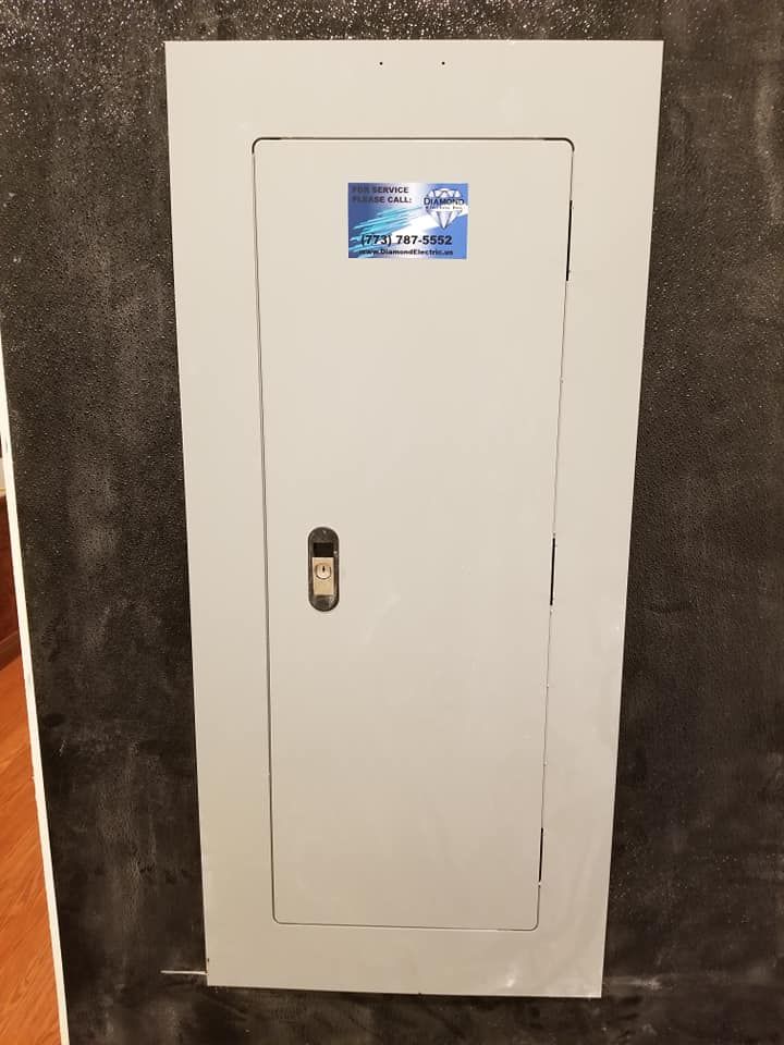 A white electrical box is sitting on a black wall.