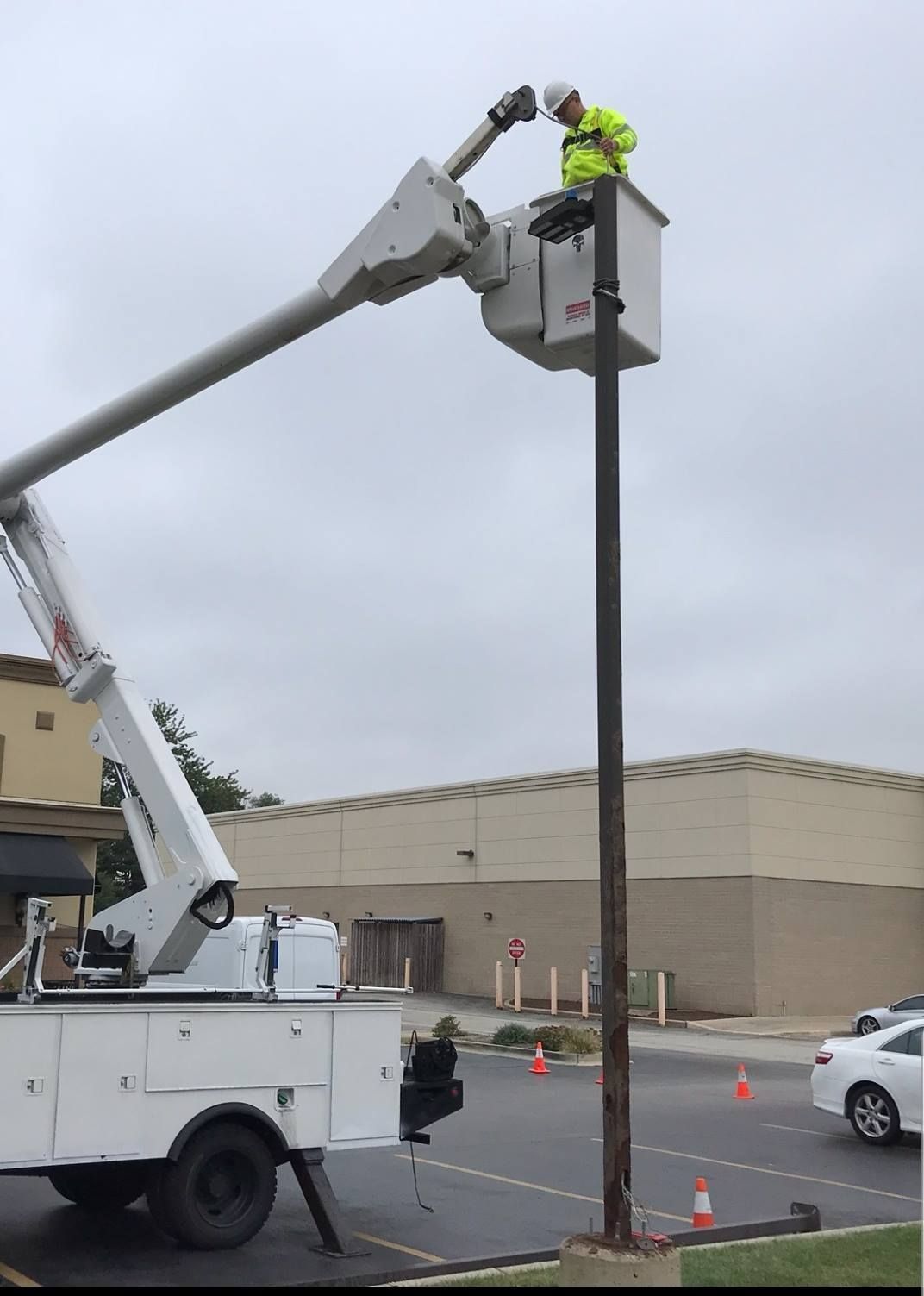 A man is standing in a bucket on top of a pole