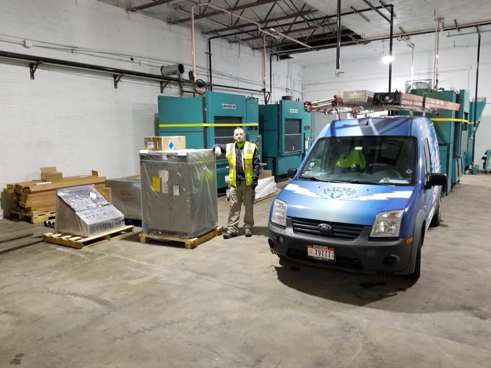 Two men are standing next to a blue van in a warehouse.