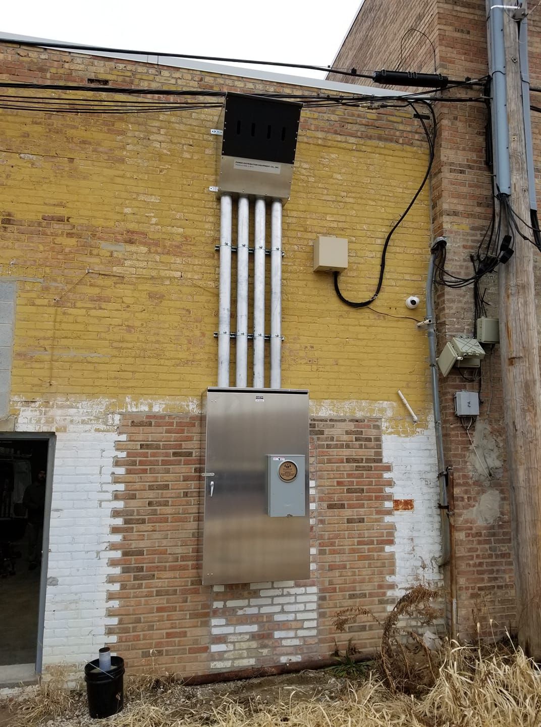 A brick building with a stainless steel box on the side of it.