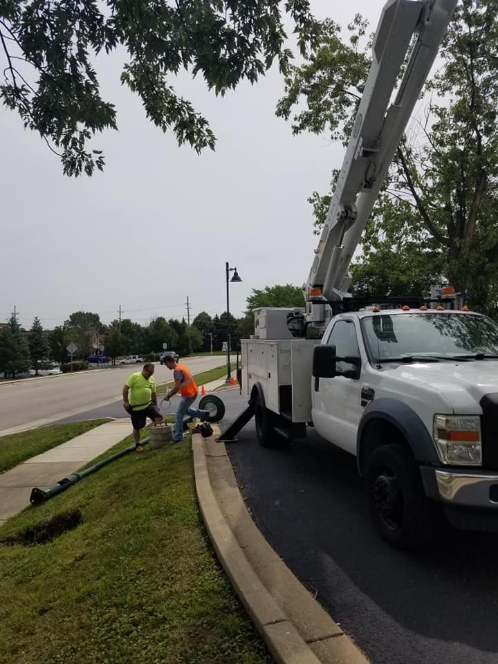 A white truck with a crane on the back is parked on the side of the road.