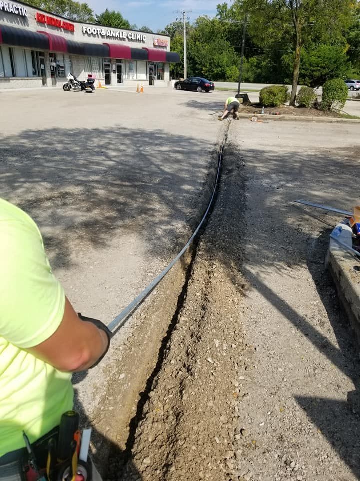 A man is digging a hole in the ground in front of a building.