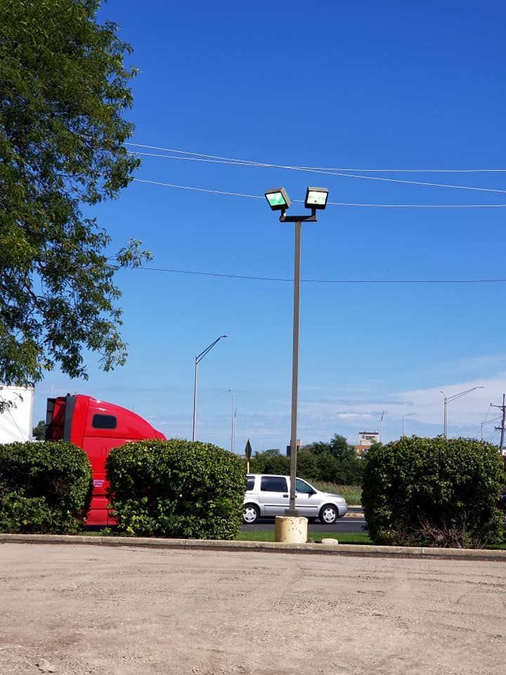 A red semi truck is parked in a parking lot next to a street light