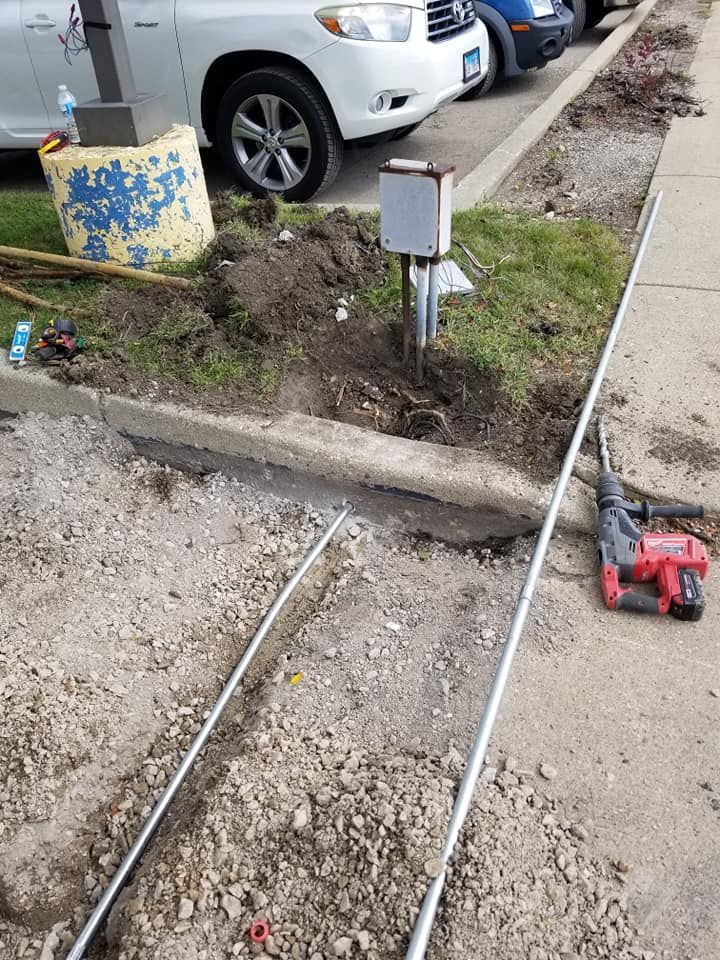 A red drill is sitting on the sidewalk next to a car.