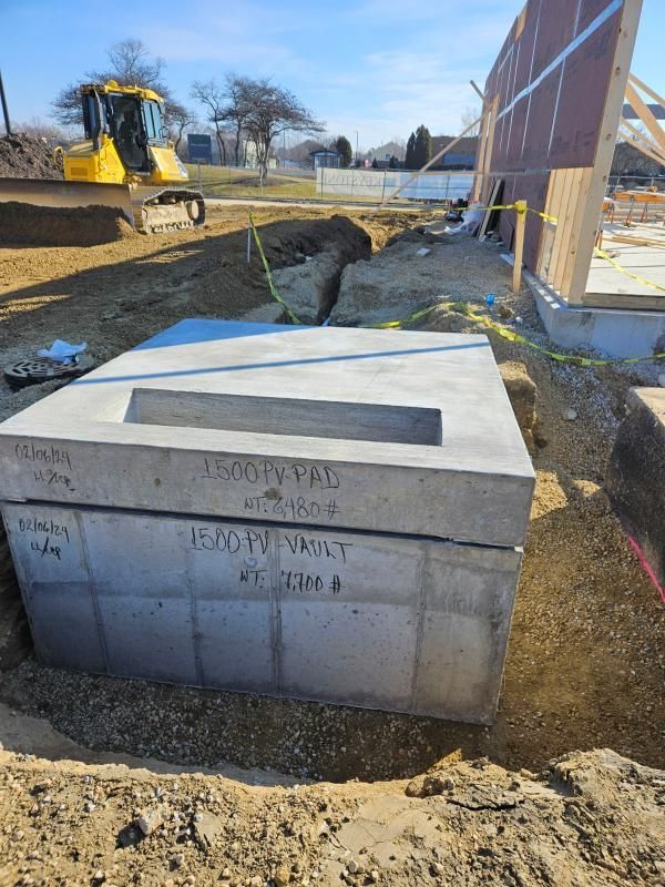 A large concrete block is sitting in the dirt in front of a building under construction.