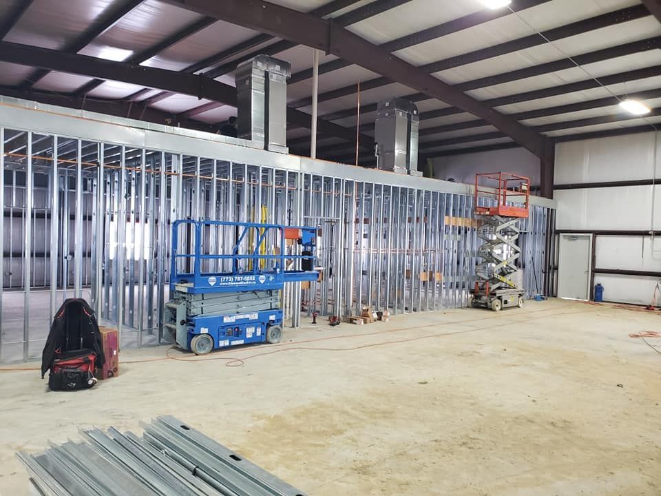 A large building under construction with a blue scissor lift in the middle.