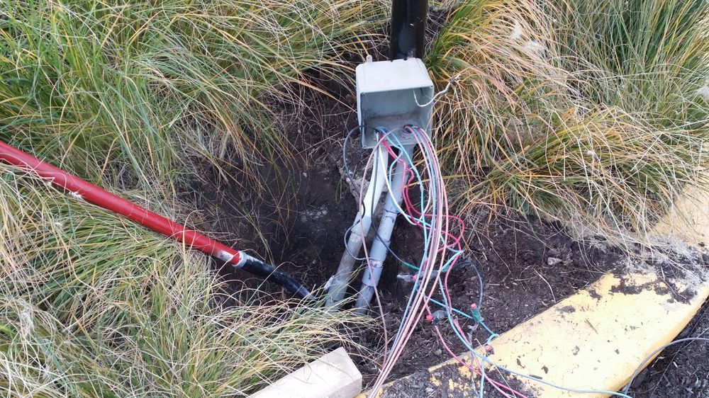 A bunch of wires are sticking out of a hole in the ground.