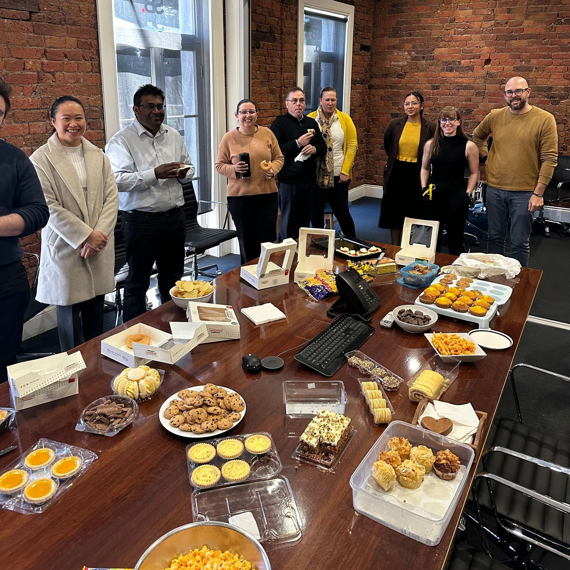 A group of people are standing around a table filled with food.