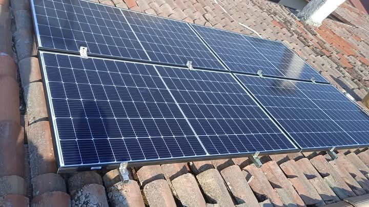 Pannelli solari montati su un tetto di tegole rosse, orientati verso il sole.