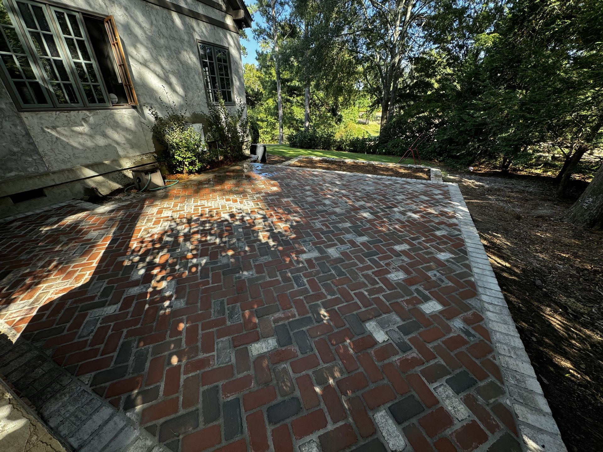 a patio with a couch , table and umbrella in a garden .