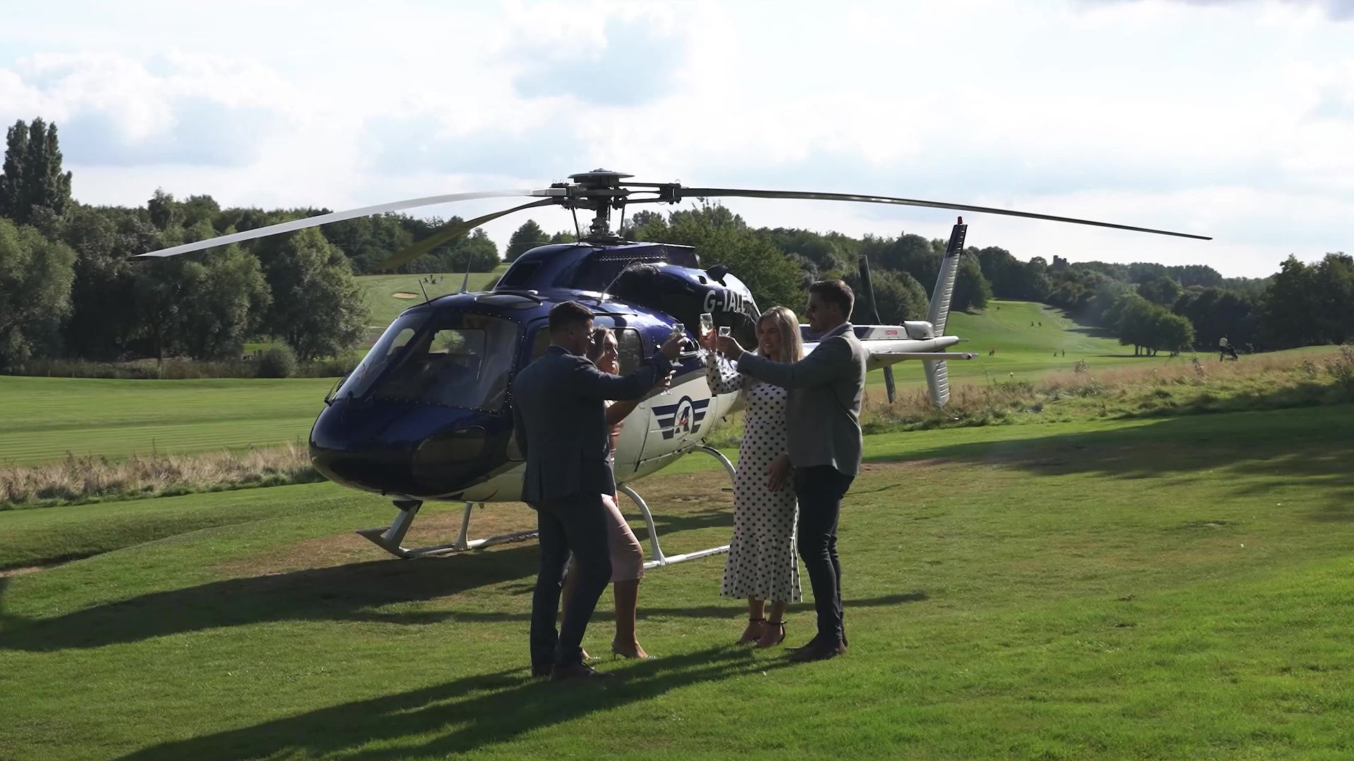 A group of people are standing in front of a helicopter in a field.
