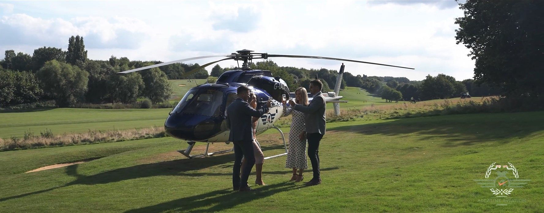 A couple is standing next to a helicopter in a field.