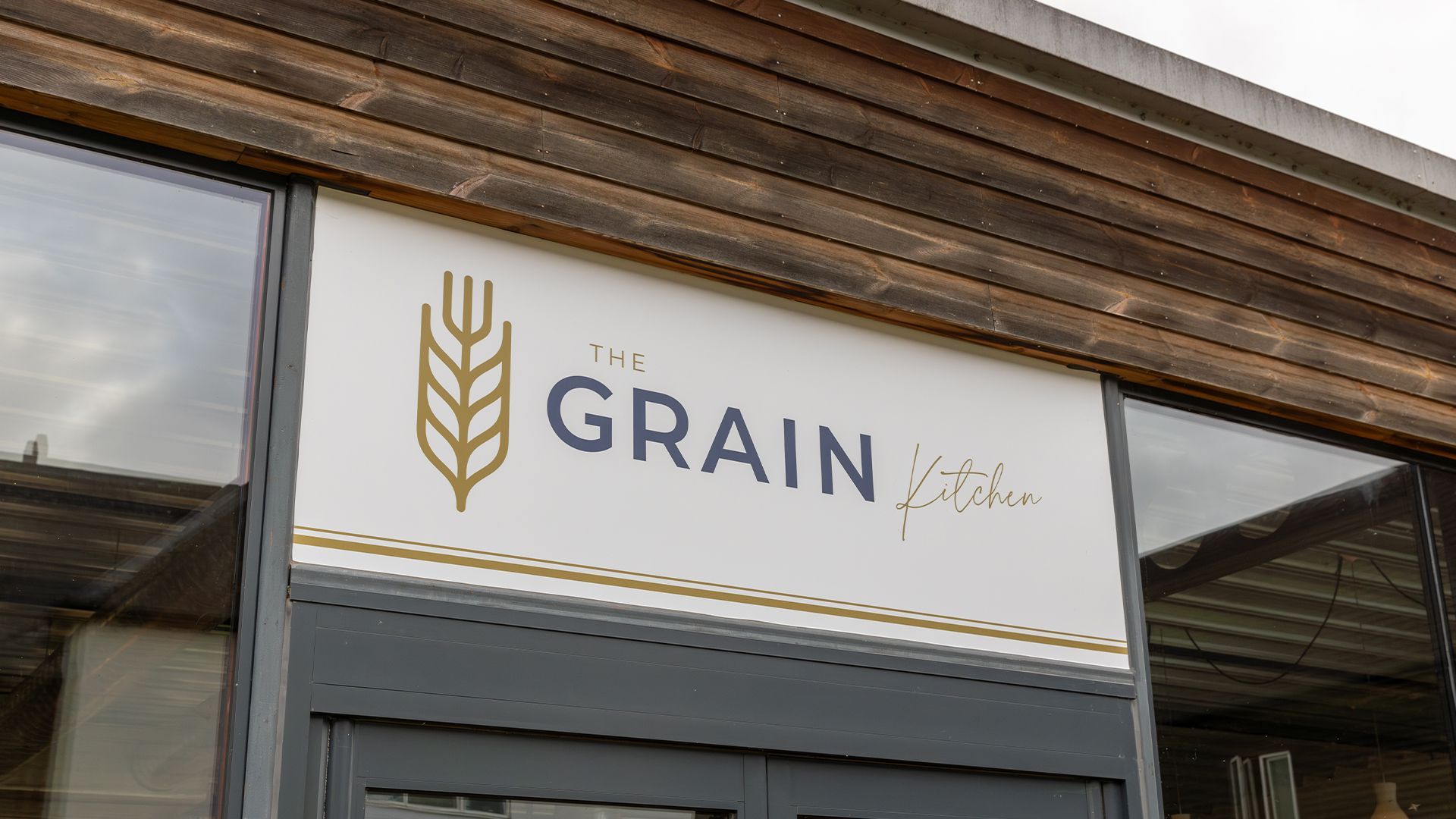 A white sign with a wheat ear on it is on the side of a building.