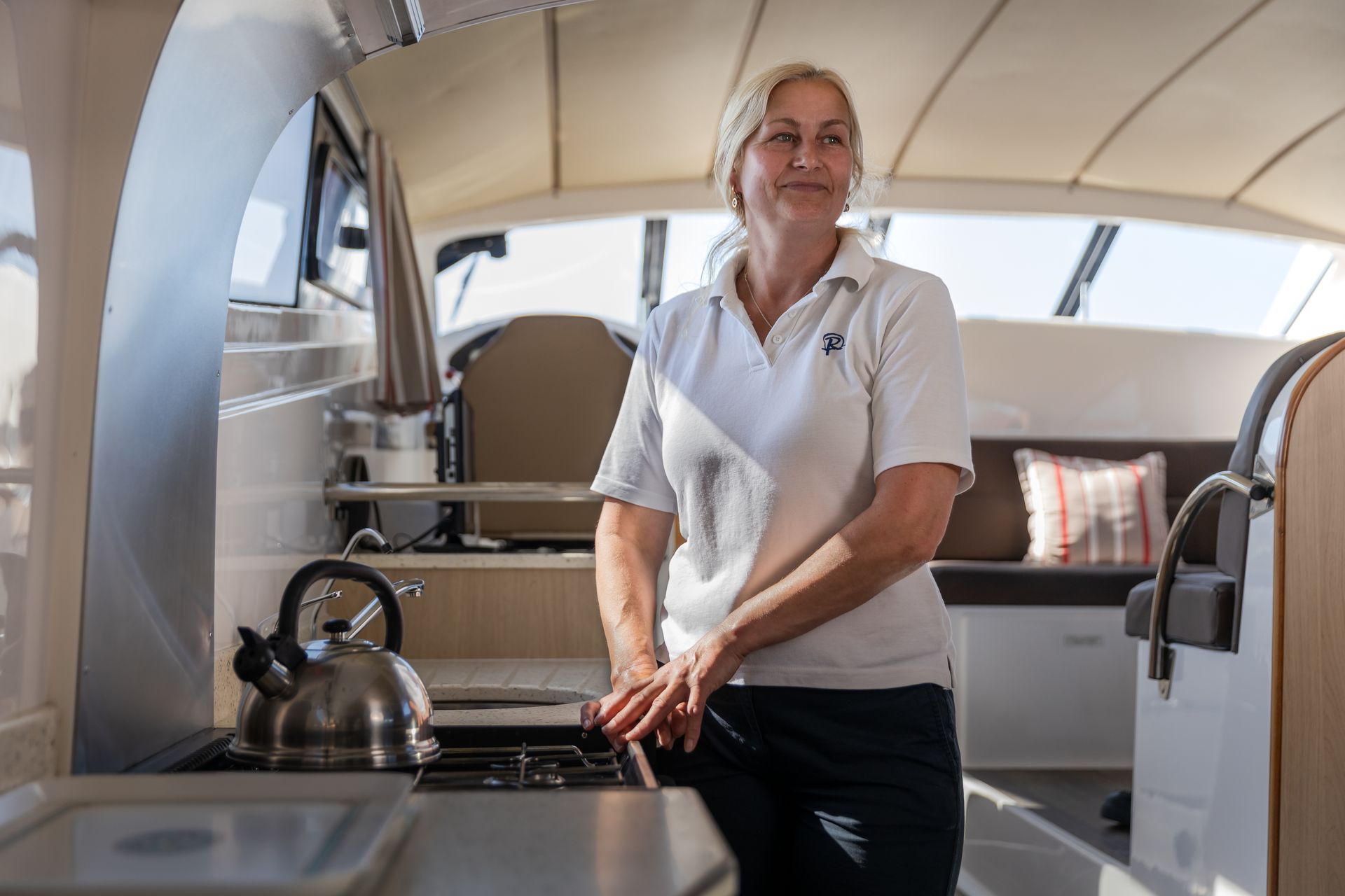 A woman is standing in a kitchen on a boat.