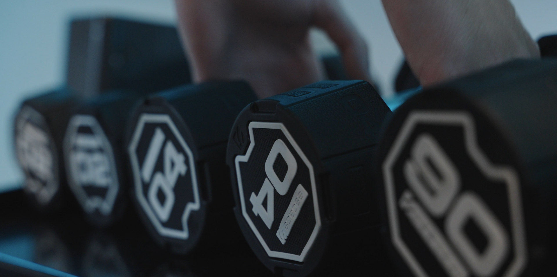 A row of black dumbbells with white numbers on them.