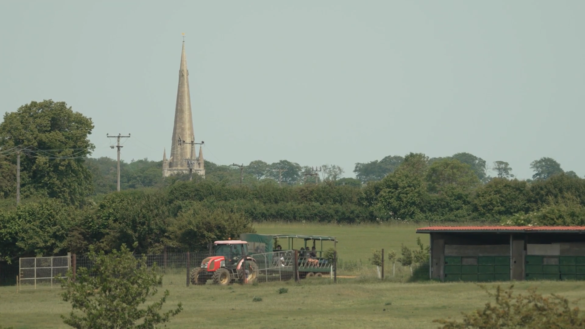 A tractor is plowing a field with a church in the background.