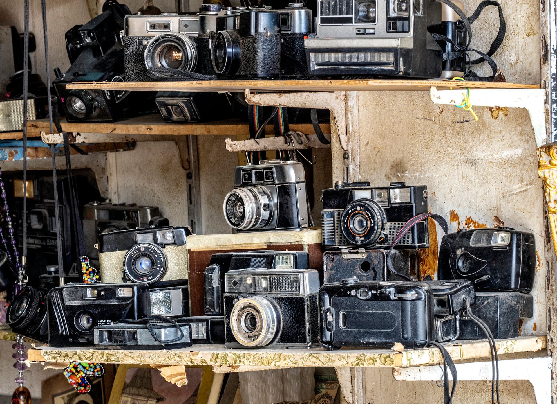 A bunch of old cameras are sitting on a shelf.