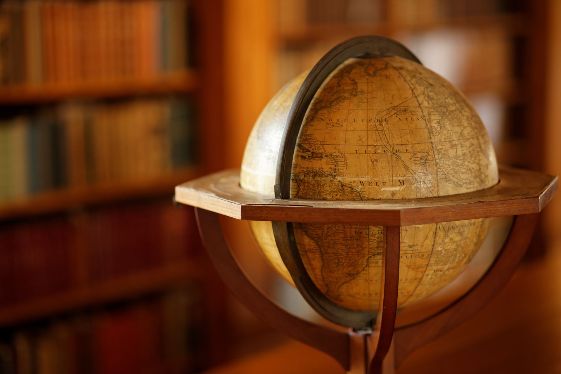 A globe is sitting on a wooden stand in a library.