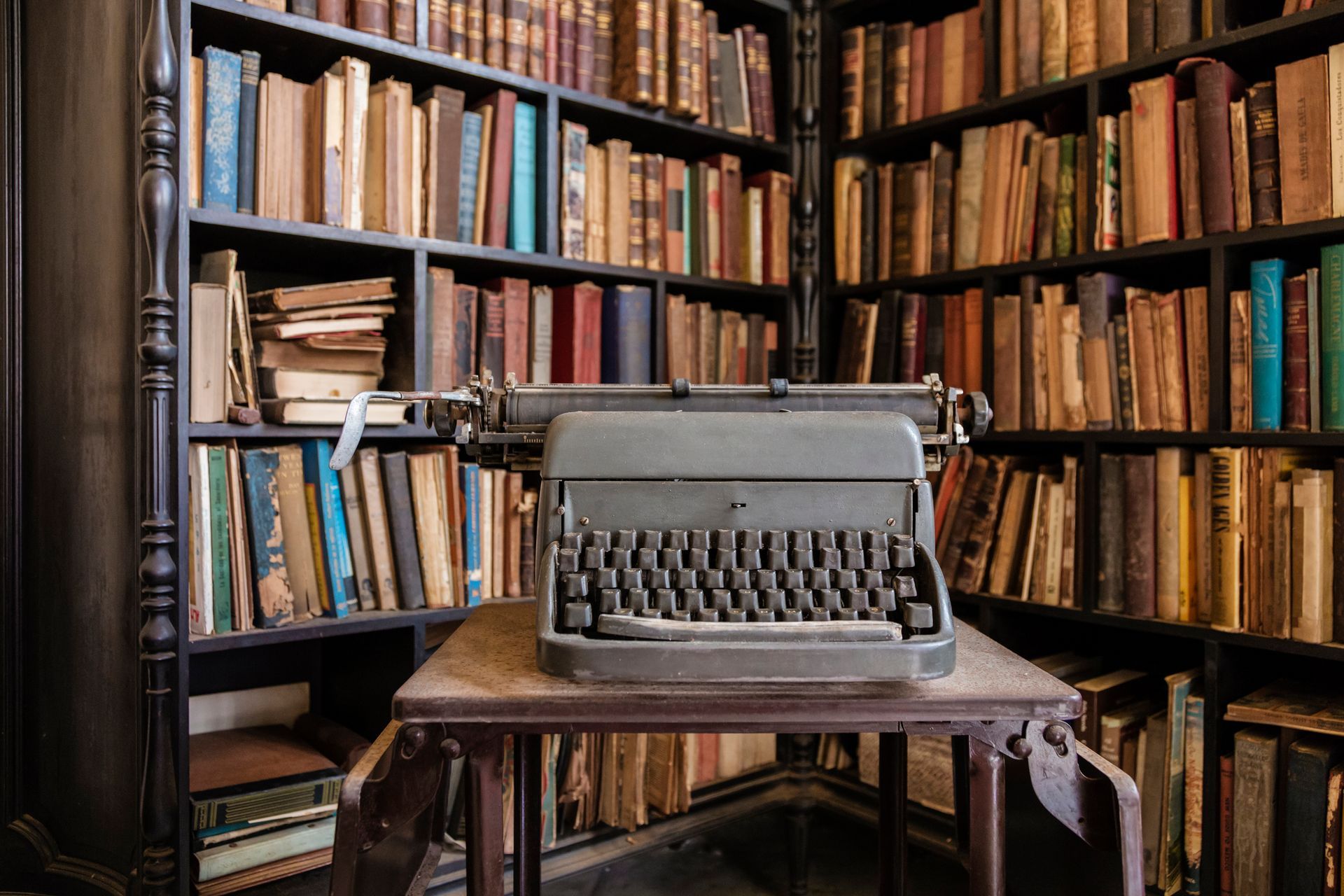 An old typewriter is sitting on a wooden table in a library.
