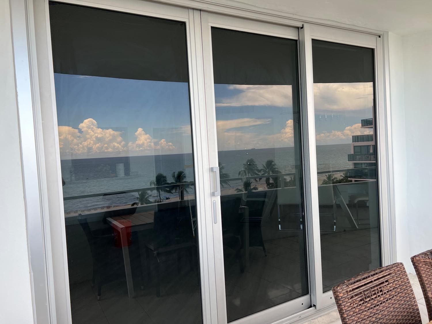 Sliding glass doors reflecting a balcony and ocean view at sunset