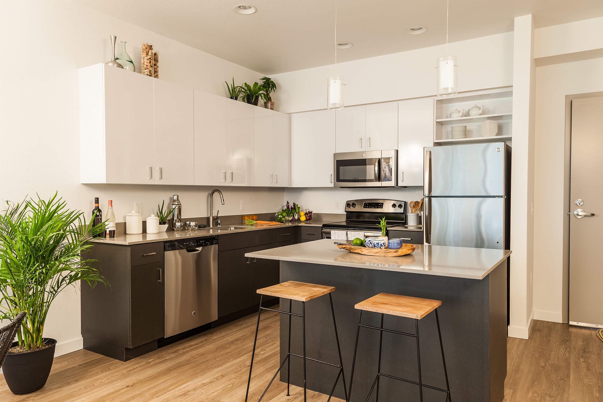 Modern kitchen with white cabinets, black island, stainless appliances, and stools by the counter