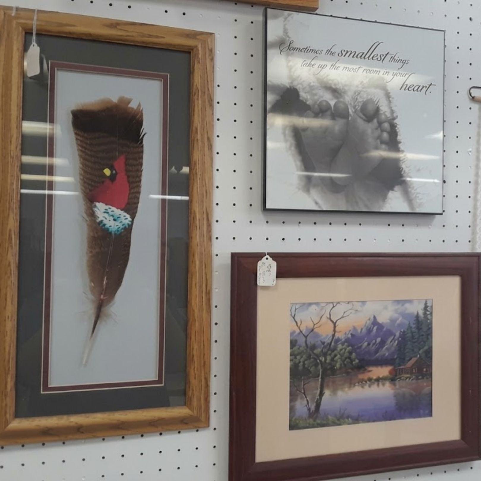 Three framed artworks hanging on a pegboard display wall.