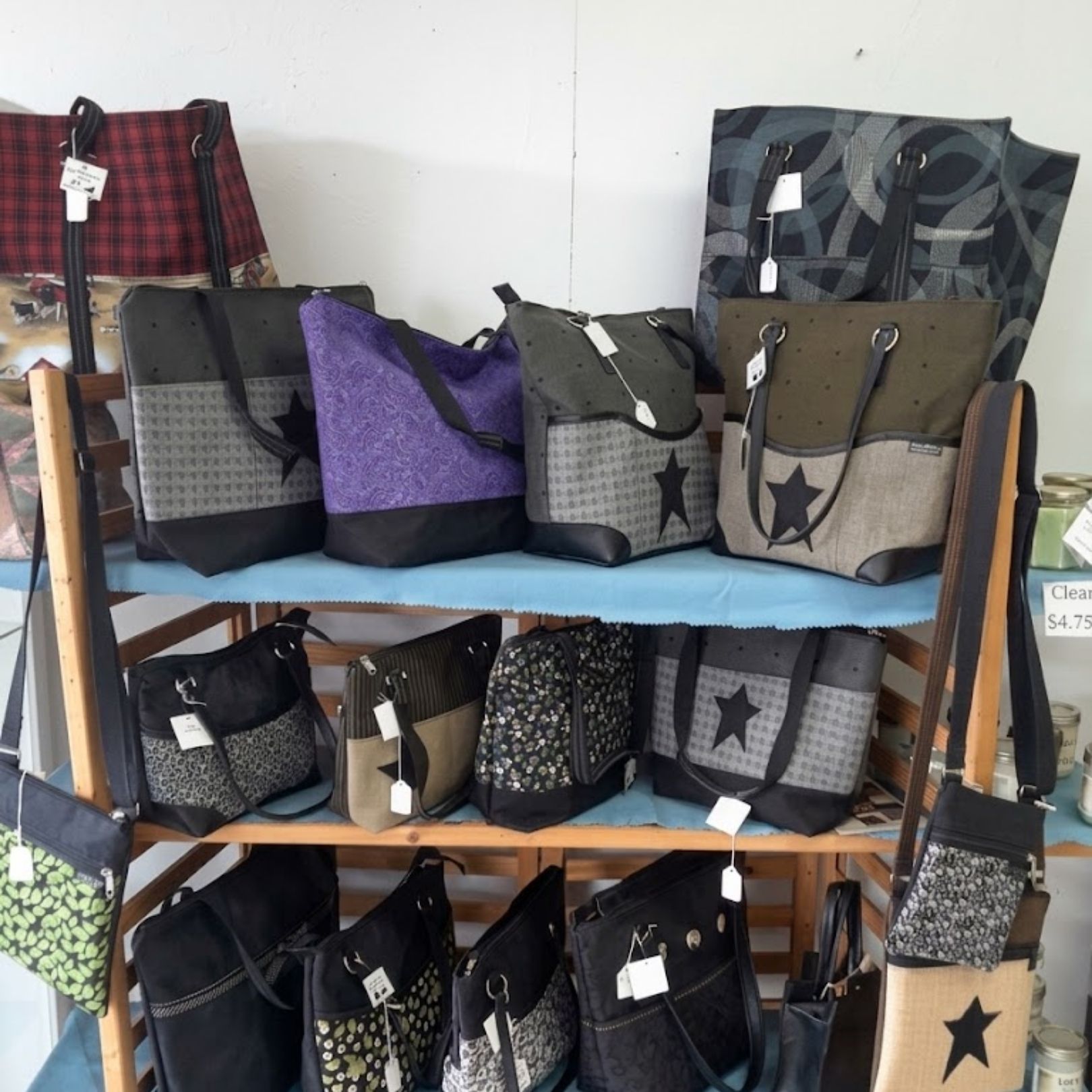 Display of assorted patterned tote bags on shelves, in black, gray, purple, and tan.