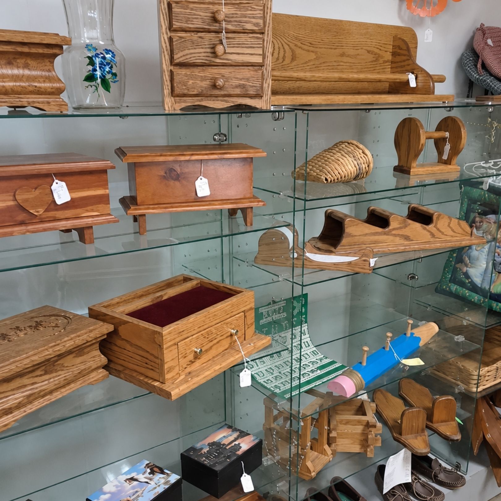 Wooden handmade crafts and small boxes displayed on glass shelves in a shop.