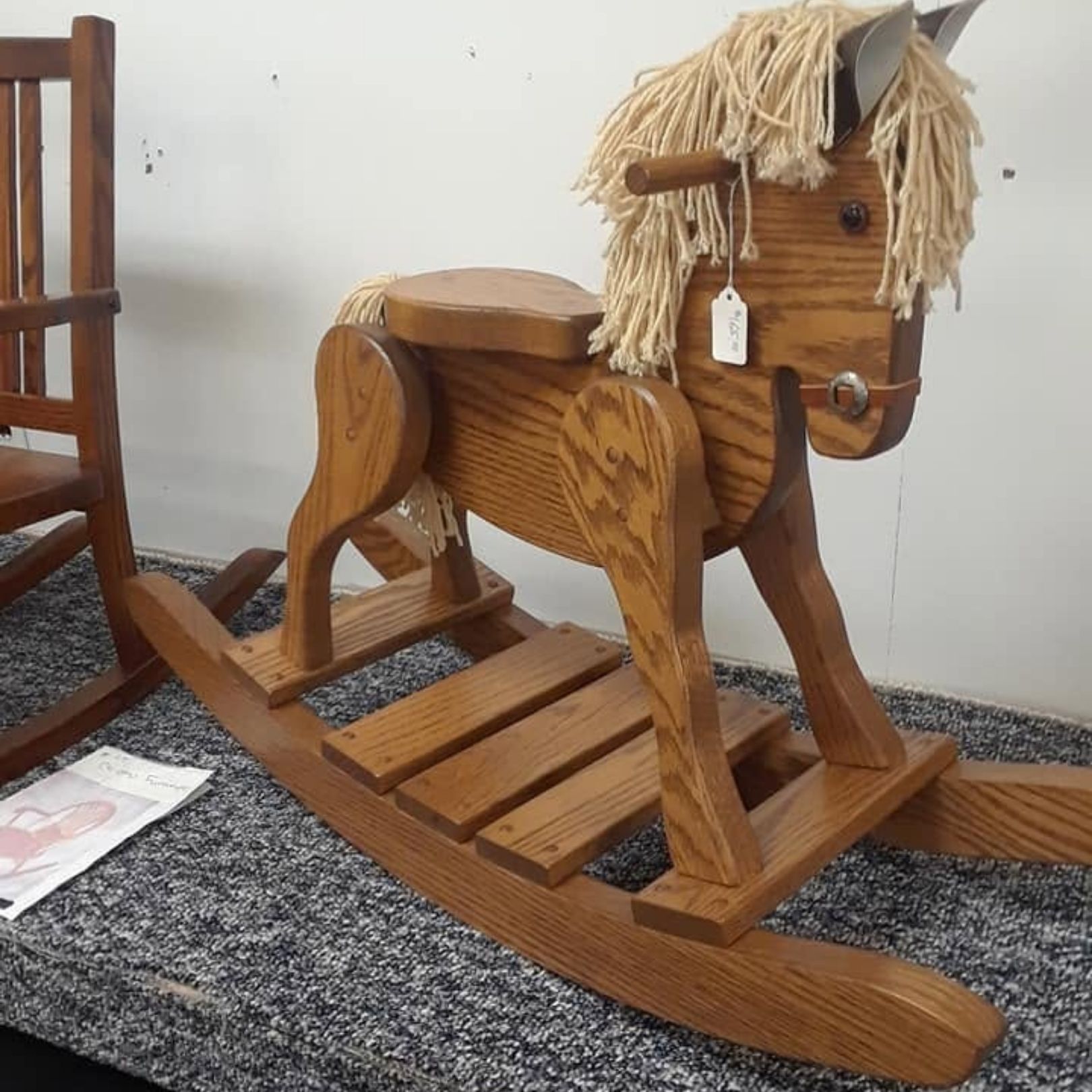 Wooden rocking horse toy with straw mane on a carpeted floor indoors