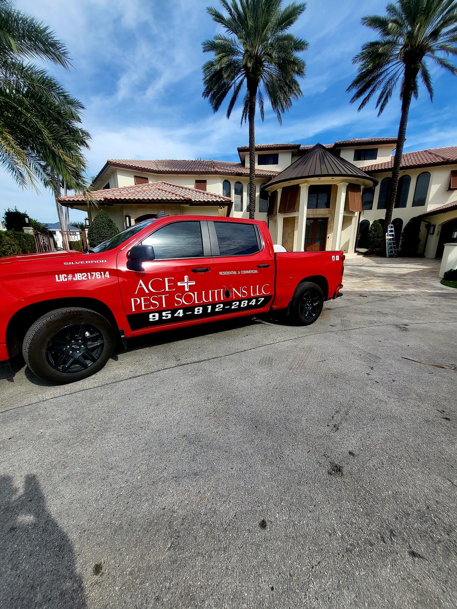 A red truck is parked in front of a building with palm trees.
