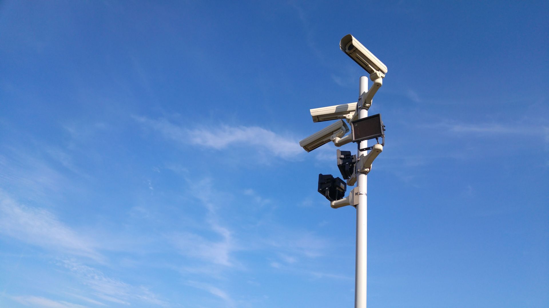 Cluster of surveillance cameras mounted on a pole against a blue sky