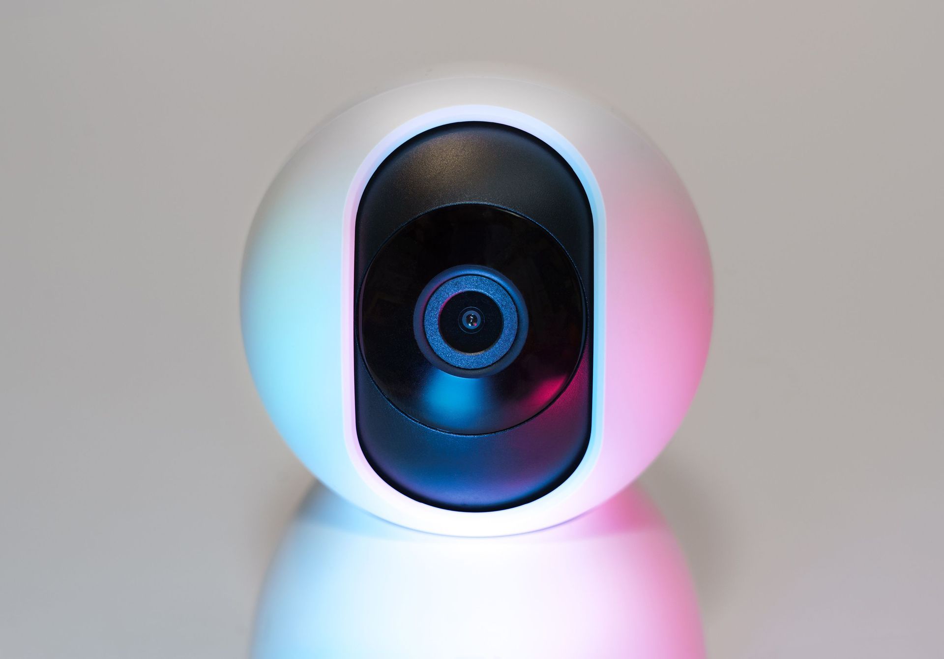 Small black camera in a white spherical housing with blue and pink LED glow