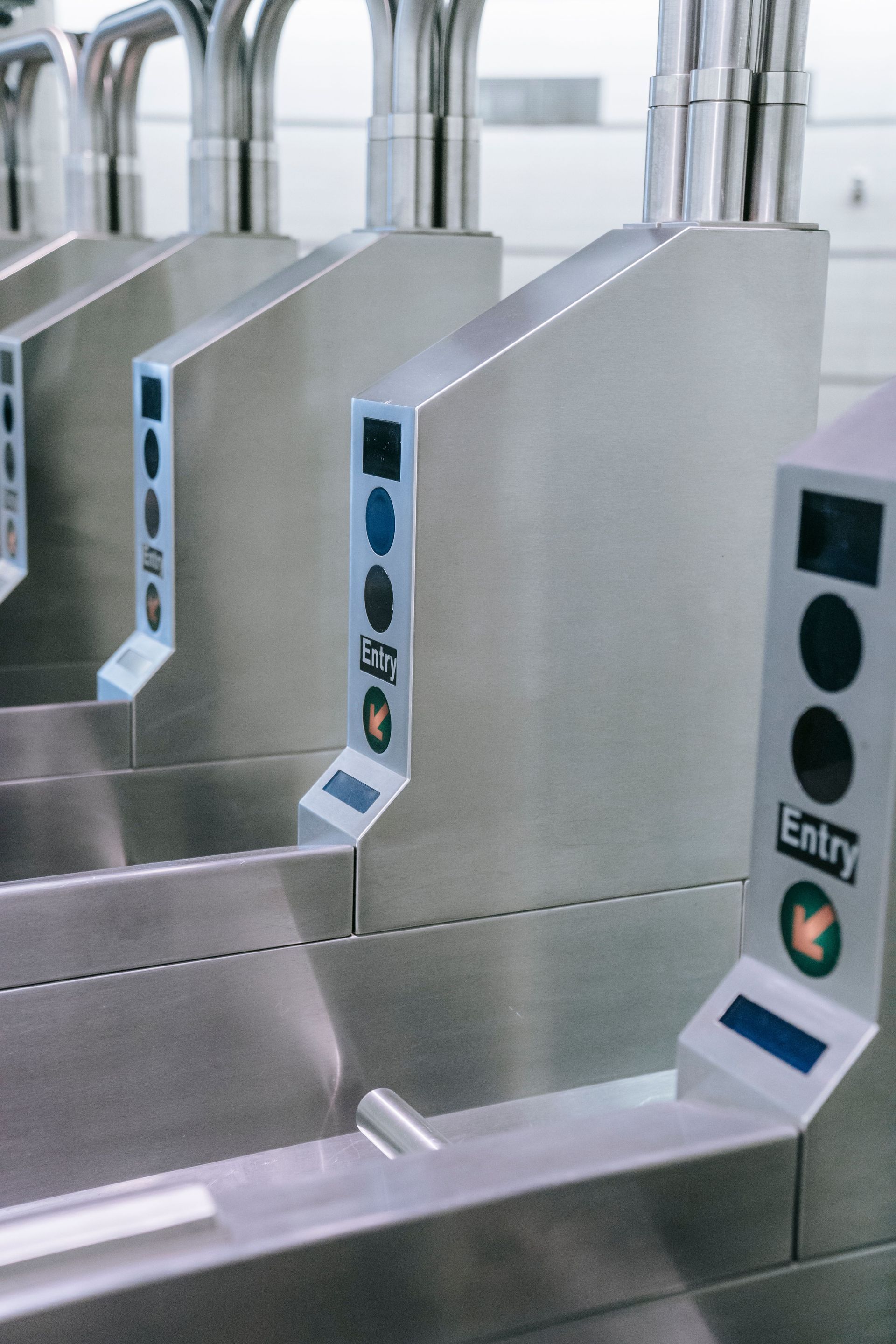 Silver turnstiles with green indicator lights at a subway or station entrance