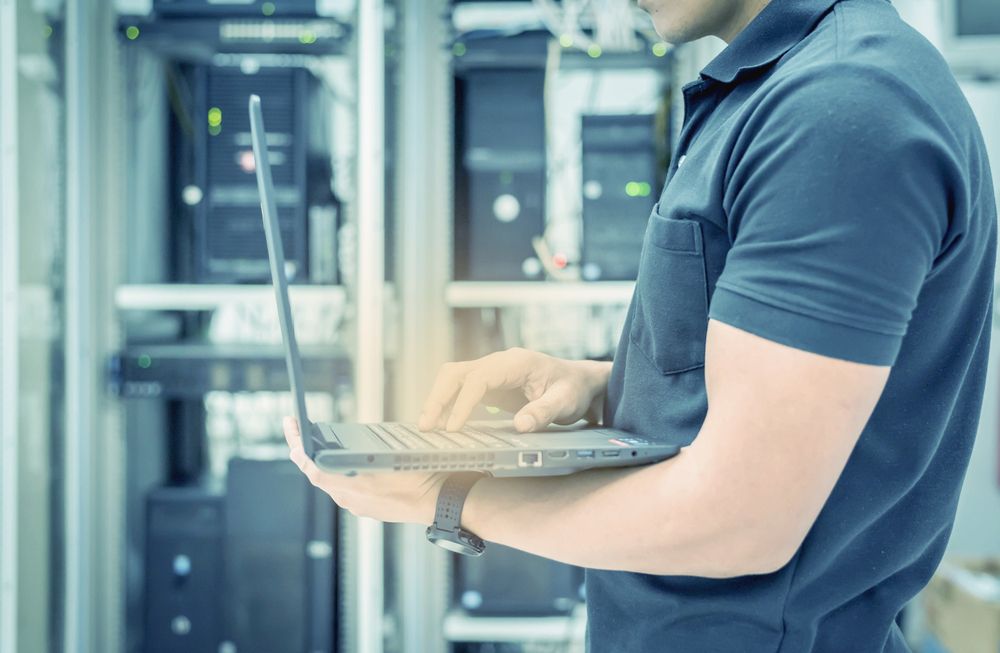 A Man is Using a Laptop Computer in a Server Room — Coastal Computing Solutions in Harrington, NSW