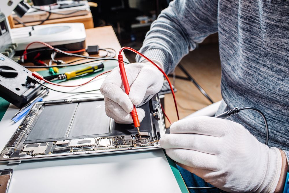 A Man Wearing White Gloves is Working on a Laptop Computer — Coastal Computing Solutions in Tuncurry, NSW