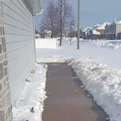 Un trottoir couvert de neige à côté d'une maison.
