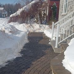 Il y a beaucoup de neige sur le trottoir et les escaliers.