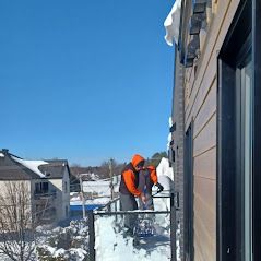 Un homme pellete la neige du toit d'un immeuble.