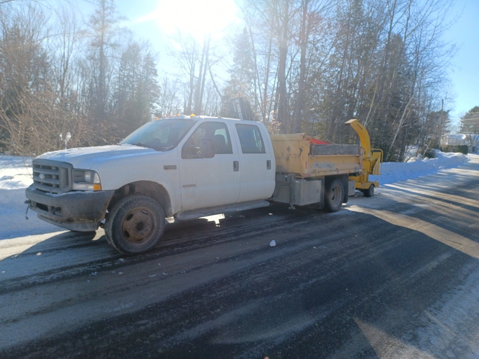 Un camion blanc avec une remorque jaune est garé sur le bord de la route.