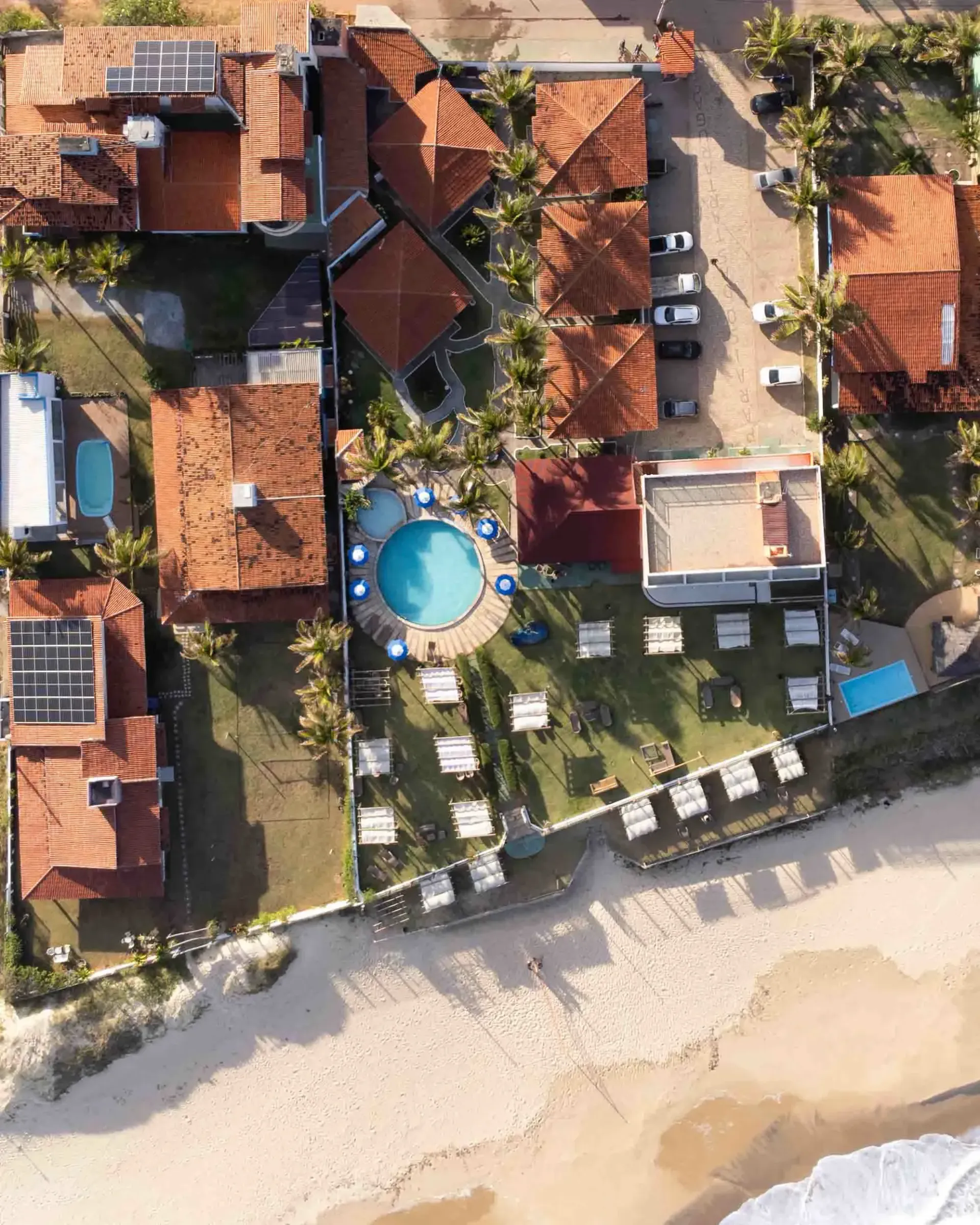 Prédio branco com área de estar coberta em gramado verde sob céu azul.