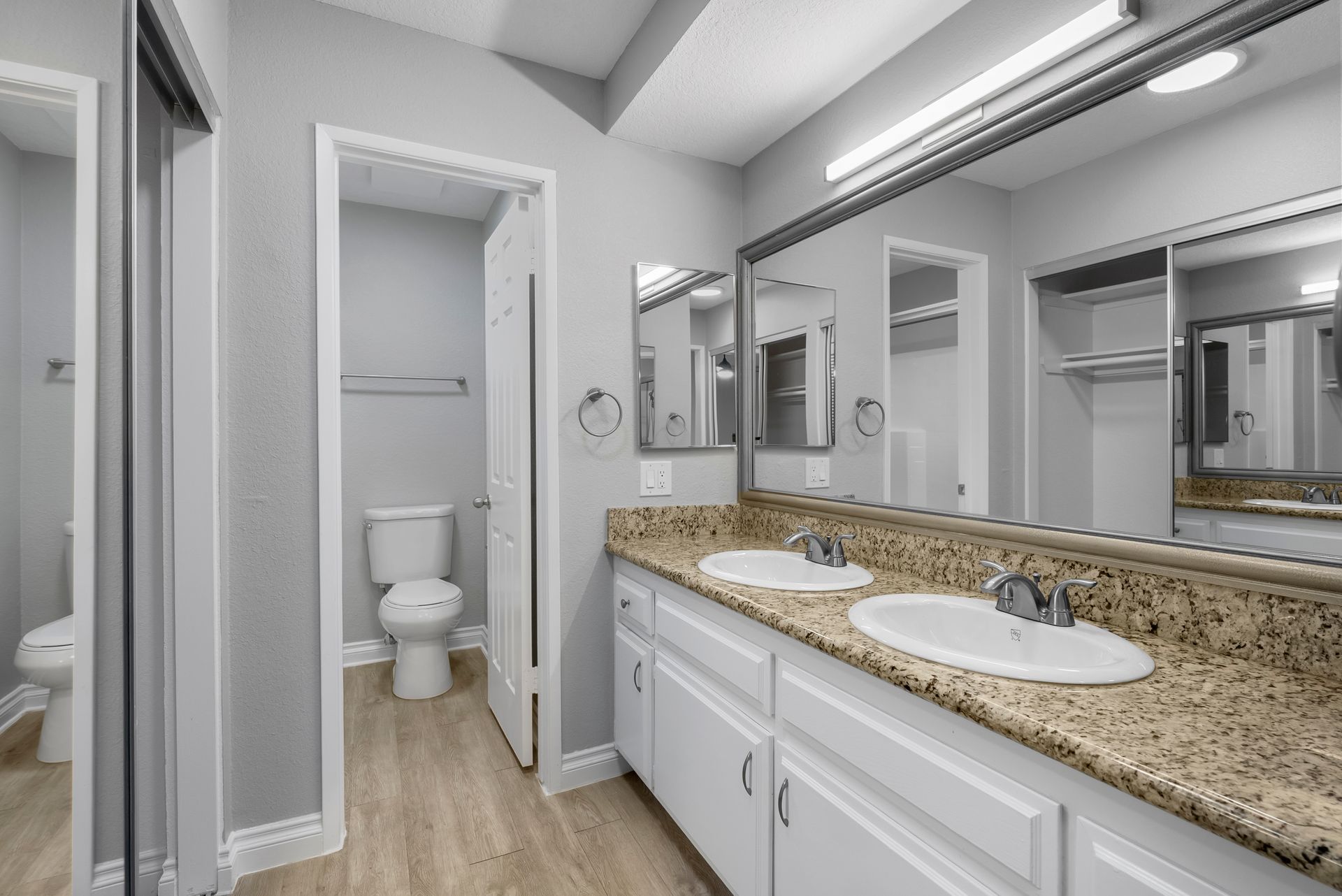 dual sinks and doorway with toilet